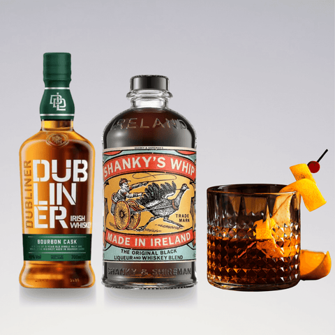 Bottles of Dubliner Irish whiskey and Shanky's Whip with a served Irishman cocktail garnished with orange peel and cherry.