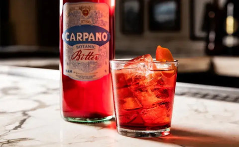 Negroni cocktail with Carpano Botanic Bitter on a marble counter, ideal for home mixing.