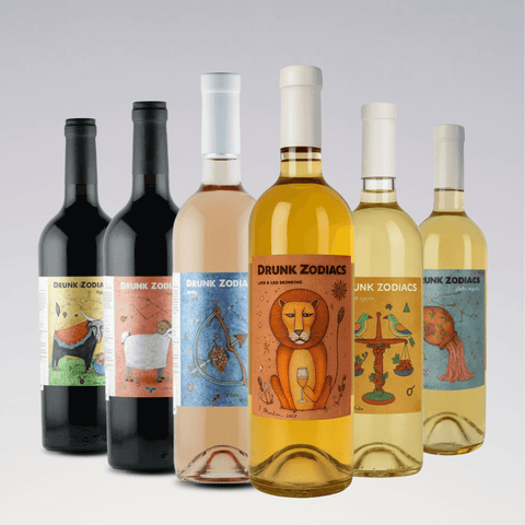 Drunk Zodiacs Collection bottles with whimsical zodiac hand-illustrated labels, featuring Leo, Libra, Aries, and Aquarius astrological signs.