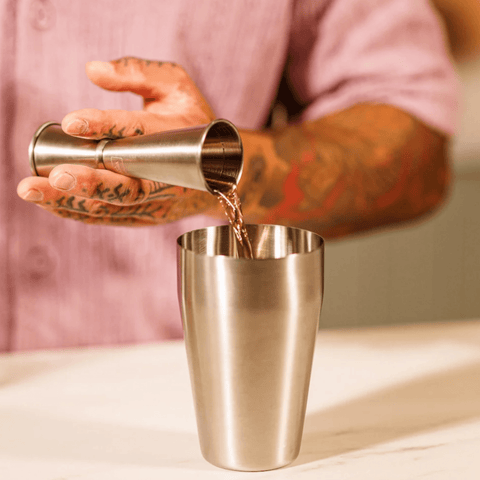 Bartender using Vacu Vin Japanese Style Jigger 30/60 ml to pour liquid into a shaker, showcasing stainless steel cocktail measure tool.