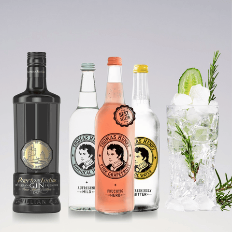 Gin and Tonic ingredients with Puerto de Indias Gin and Thomas Henry Tonic bottles, garnished cocktail glass with cucumber and rosemary.